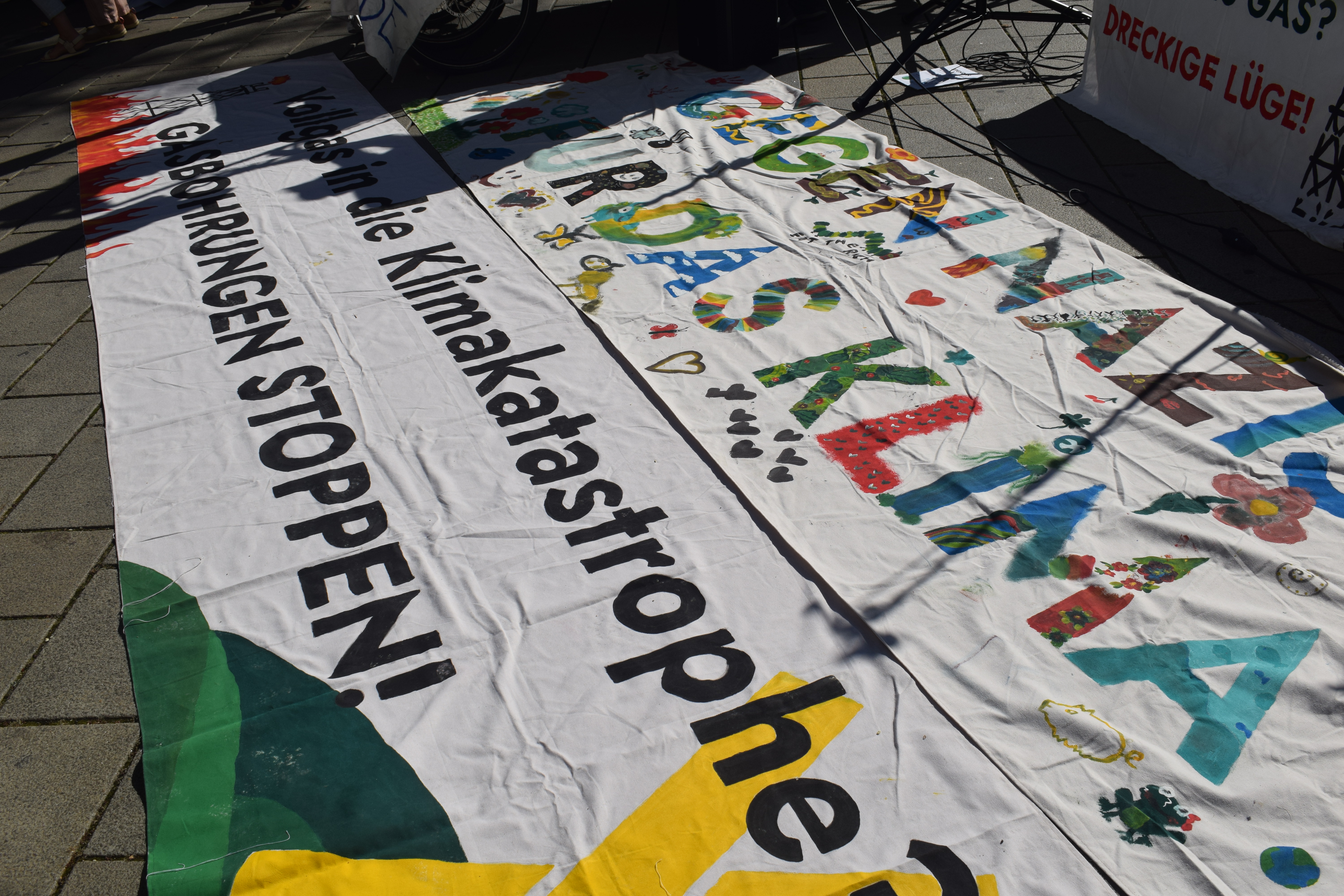 Zwei Banner am Boden: Gegen Nazis für das Klima und Vollgas in die klimakatastrophe Gasbohrungen Stoppen